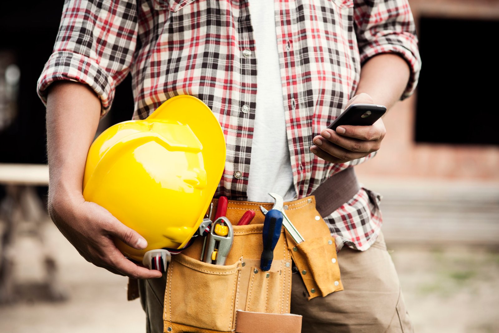 close up of construction worker texting on mobile phone